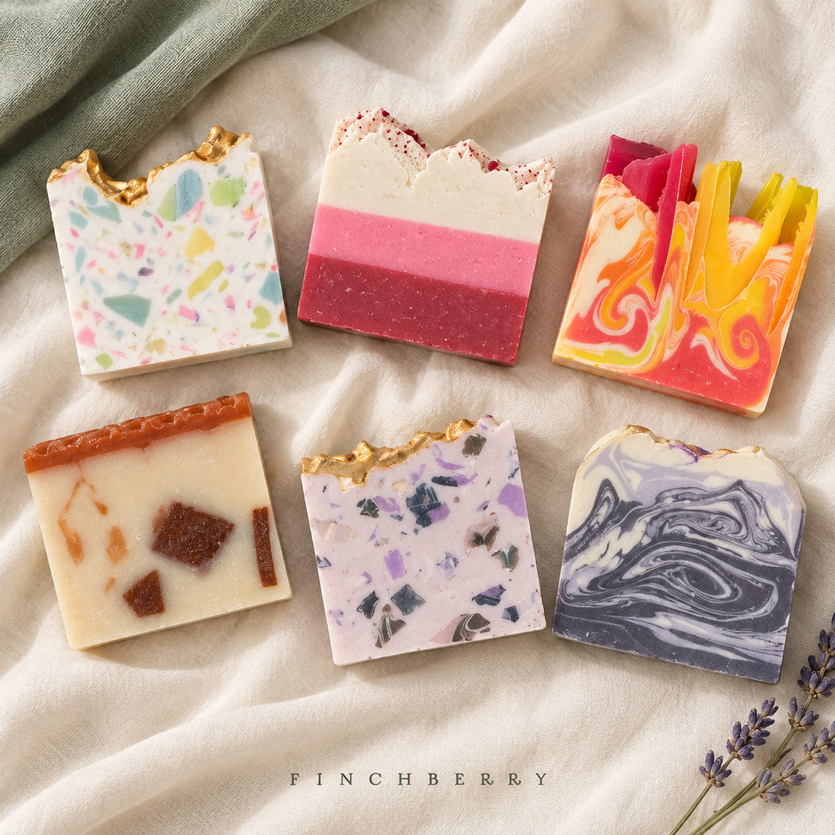 Six unboxed Finchberry soaps on ivory fabric with sage cloth and lavender