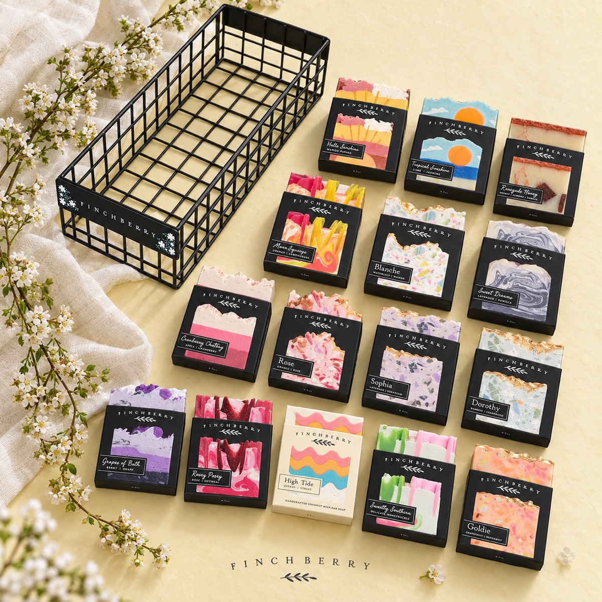 Fifteen Finchberry soaps and black wire display basket on a pale yellow botanical background